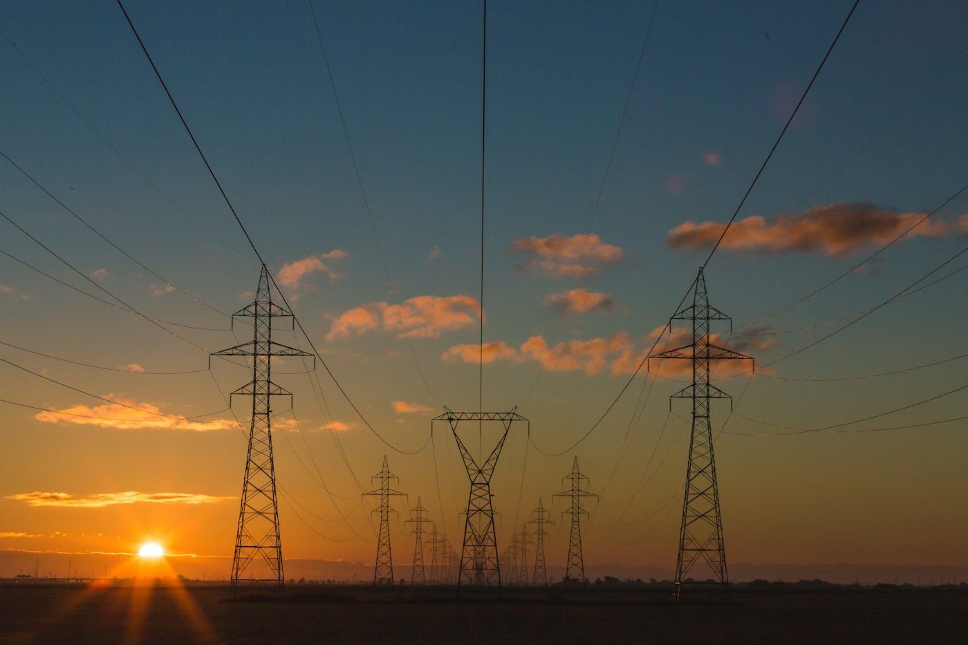 High-voltage electricity transmission towers against a warm sunset sky